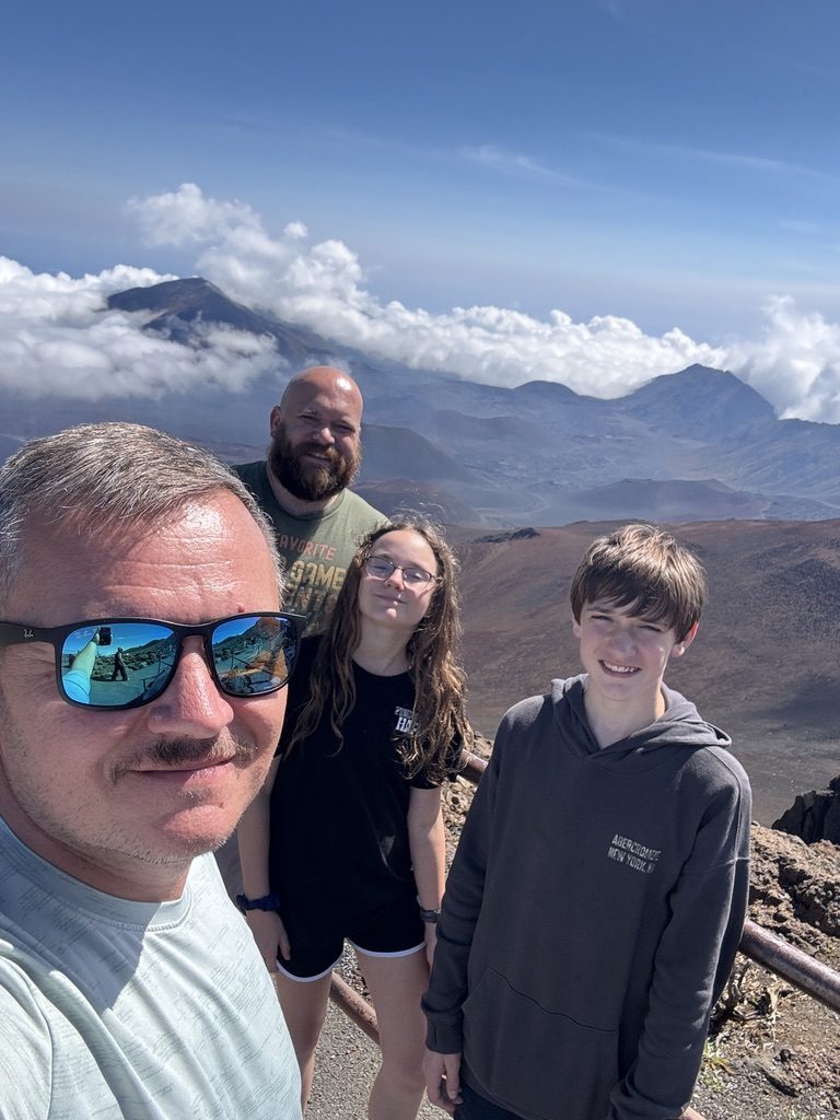 Aaron and Josh with their two kids at a mountain overlook above the clouds